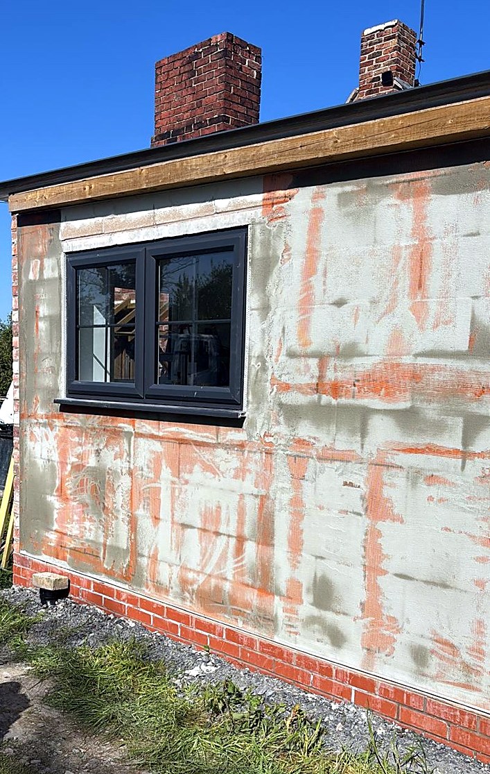 Basecoat and reinforcing mesh applied over insulation boards