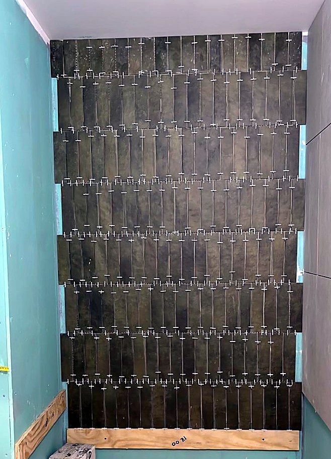 Green vertical feature tiles being laid with levelling clips
